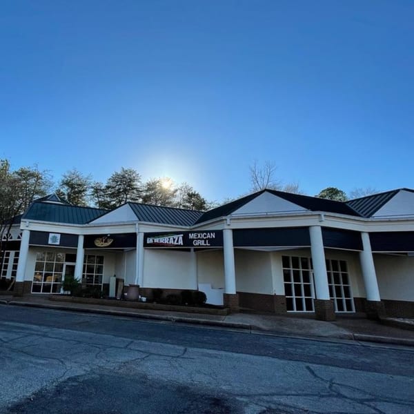 Exterior of La Terraza Mexican Grill, a white building with dark blue accents and large windows.