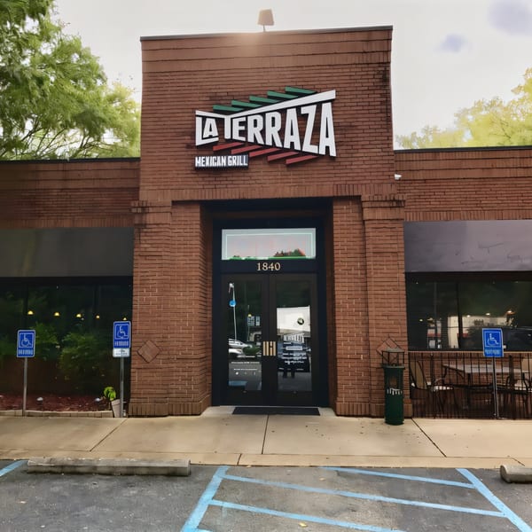 The brick exterior of La Terraza Mexican Grill, featuring its sign, entrance, and outdoor seating.